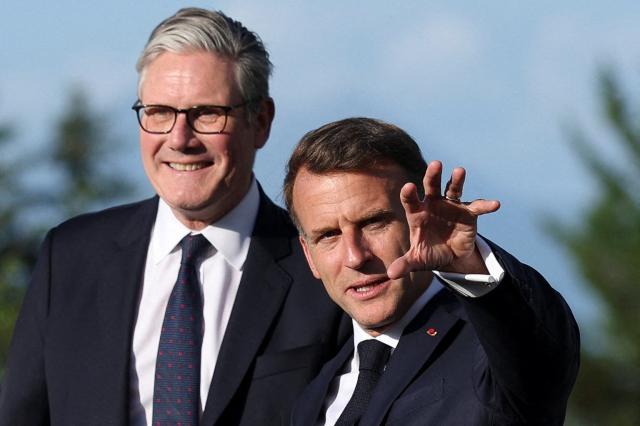 France's President Emmanuel Macron (R) gestures next to Britain's Prime Minister Keir Starmer during the official greeting as part of the G7 summit, in Evian, eastern France, on June 15, 2026. A G7 summit is set to take place June 15 to 17 in the French town of Evian-les-Bains near Switzerland and it will be attended by country leaders as well as the EU's foreign policy chief and ministers from Brazil, Canada, the United Arab Emirates and Turkey. (Photo by Isabel Infantes / POOL / AFP)