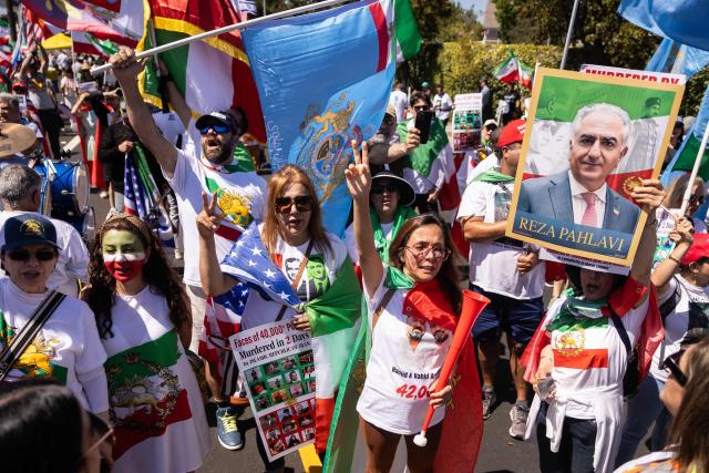 A protester holds a sign with a portrait of the son of the last shah of Iran,  Reza Pahlavi, as people demonstrate against the Iranian regime outside Los Angeles Stadium (SoFi Stadium) ahead of the 2026 World Cup football tournament match between Iran and New Zealand in Inglewood, California, on June 15, 2026. Hundreds of anti-regime protesters gathered outside the stadium in Los Angeles Monday where Iran will take on New Zealand in their opening game of the 2026 World Cup. (Photo by ETIENNE LAURENT / AFP)