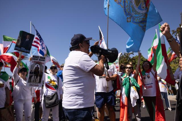 A man speaks into a megaphone as people demonstrate against the Iranian regime outside Los Angeles Stadium (SoFi Stadium) ahead of the 2026 World Cup football tournament match between Iran and New Zealand in Inglewood, California, on June 15, 2026. Hundreds of anti-regime protesters gathered outside the stadium in Los Angeles Monday where Iran will take on New Zealand in their opening game of the 2026 World Cup. (Photo by ETIENNE LAURENT / AFP)