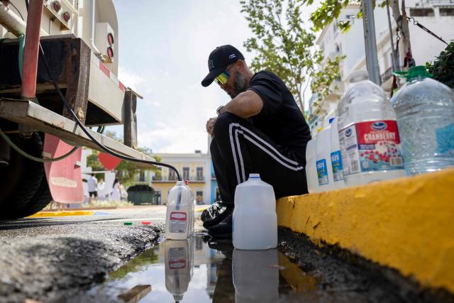 A man fills water containers from a tanker truck amid ongoing water shortages in Old San Juan, Puerto Rico, on June 15, 2026. Three major ruptures in a 72-inch pipeline, detected by authorities on June 10, 2026, has severely disrupted potable water service across the San Juan metropolitan area, affecting more than 100,000 customers. (Photo by Ricardo ARDUENGO / AFP)