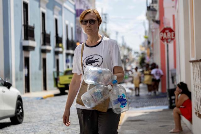 A resident carry water containers to be filled from a tanker truck supplying potable water during ongoing water shortages in Old San Juan, Puerto Rico, on June 15, 2026. Three major ruptures in a 72-inch pipeline, detected by authorities on June 10, 2026, has severely disrupted potable water service across the San Juan metropolitan area, affecting more than 100,000 customers. (Photo by Ricardo ARDUENGO / AFP)