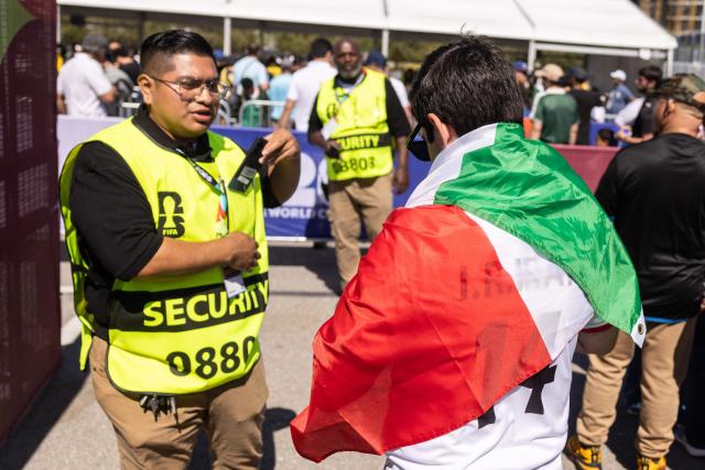 A security guard checks an Iran fans flag during a security check at Los Angeles Stadium (SoFi Stadium) ahead of the 2026 World Cup Group G football match between Iran and New Zealand in Inglewood, California, on June 15, 2026. (Photo by ETIENNE LAURENT / AFP)