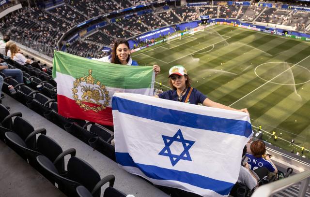Fans show a pre-revolutionary Iranian flag and an Israeli flag ahead of the 2026 World Cup Group G football match between Iran and New Zealand at Los Angeles Stadium in Inglewood on June 15, 2026.  (Photo by ETIENNE LAURENT / AFP)