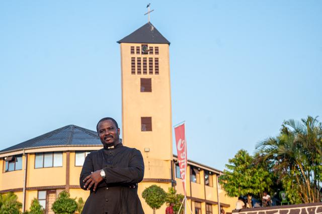 Father Jean-Pierre Mongambi, a Congolese priest who performs rap music as part of his evangelisation work, poses for a portrait in the courtyard of the Bienheureuse Anuarite parish in Kinshasa on May 17, 2026. Jean-Pierre Mongambi, also known as “the rapping priest,” roams the most deprived neighbourhoods of the Congolese capital to evangelise young people.
He has become a celebrity in the DRC, and beyond, with rap tracks that reprise psalms and prayers, and concerts widely shared on social media. (Photo by Hardy BOPE / AFP)