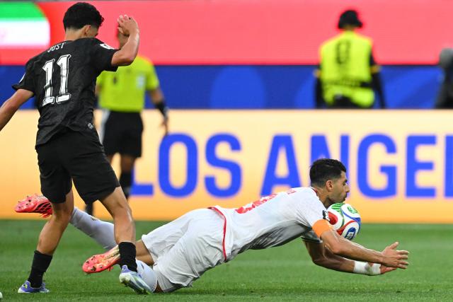 Iran's forward #09 Mehdi Taremi (R) falls on the ground past New Zealand's forward #11 Elijah Just (L) during the 2026 World Cup Group G football match between Iran and New Zealand at Los Angeles Stadium in Inglewood on June 15, 2026.  (Photo by Patrick T. Fallon / AFP)