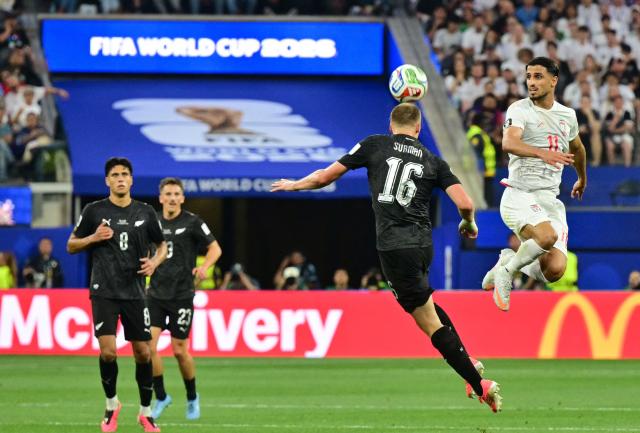 New Zealand's defender #16 Finn Surman heads the ball past Iran's forward #11 Ali Alipour during the 2026 World Cup Group G football match between Iran and New Zealand at Los Angeles Stadium in Inglewood on June 15, 2026.  (Photo by Frederic J. Brown / AFP)