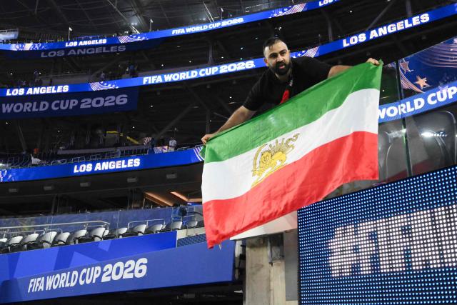 An Iranian fan shows a pre-revolutionary Iranian flag after the 2026 World Cup Group G football match between Iran and New Zealand at Los Angeles Stadium in Inglewood on June 15, 2026.  (Photo by Patrick T. Fallon / AFP)