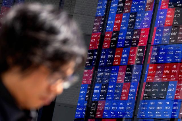 A man walks past an electronic quotation board displaying the Nikkei 225 stock prices on the Tokyo Stock Exchange in Tokyo on June 16, 2026. (Photo by Kazuhiro NOGI / AFP)