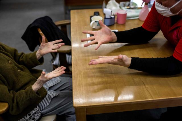 (FILES) An elderly woman (L) exercises at a day care facility for senior citizens in Tokyo on April 6, 2022. In Yo Kusakabe's taboo novel, a young doctor advocates chopping off elderly patients' useless limbs as a groundbreaking solution to super-ageing Japan's overstressed care industry. Now adapted into a film, "Haiyoshin (Useless Body)" has attracted huge controversy since its release last month in Japan, but has also focused attention on the struggling care sector in a country with the world's second-oldest population. (Photo by Behrouz MEHRI / AFP)