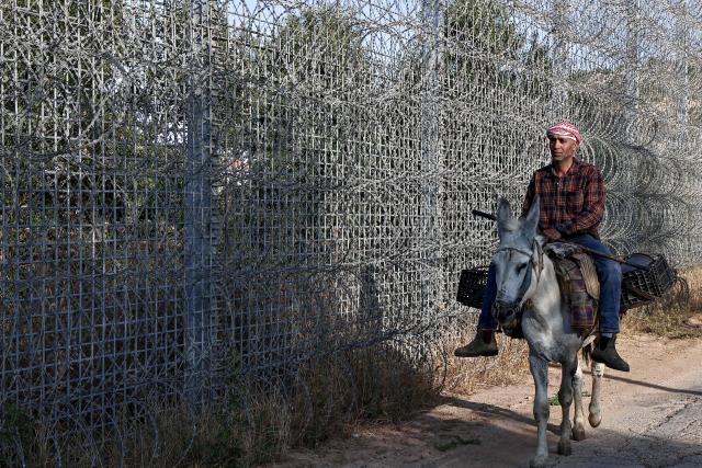 Palestinian farmer 40-year-old Mohammad Fuqaha rides his donkey along the route leading to the Israeli fenced-off area, as he heads to his farmland in the town of Sinjil, north of Ramallah in the occupied West Bank on June 15, 2026. Repeated attacks by Israeli settlers have made access to and cultivation of the land increasingly perilous. The occupied West Bank has been gripped by almost daily violence involving Israeli troops and settlers since the start of the Gaza war in October 2023. (Photo by Zain JAAFAR / AFP)