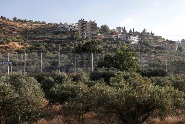 A metal fence is erected by the Israeli military around the Palestinian village of Sinjil, separating it's inhabitants from their farm land, north of the occupied West Bank city of Ramallah on June 15, 2026. The occupied West Bank has been gripped by almost daily violence involving Israeli troops and settlers since the start of the Gaza war in October 2023. (Photo by Zain JAAFAR / AFP)