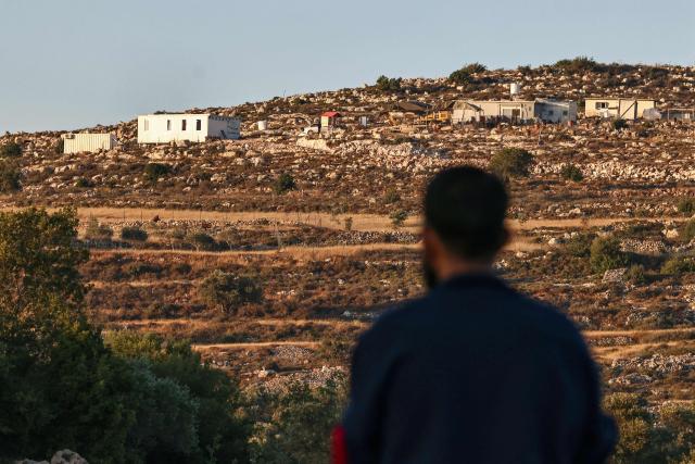 A Palestinian man stands looking at a newly established Israeli settlement outpost north of the town of Sinjil, north of Ramallah in the occupied West Bank, on June 15, 2026. The occupied West Bank has been gripped by almost daily violence involving Israeli troops and settlers since the start of the Gaza war in October 2023. (Photo by Zain JAAFAR / AFP)