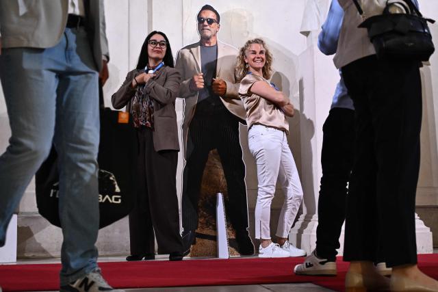 Attendees arriving for the Schwarzenegger climate initiative conference pose with a cut out figure of Arnold Schwarzenegger in Vienna, Austria on June 16, 2026. Former actor and politician Arnold Schwarzenegger hosts an annual conference on climate change in his native country. (Photo by Joe Klamar / AFP)