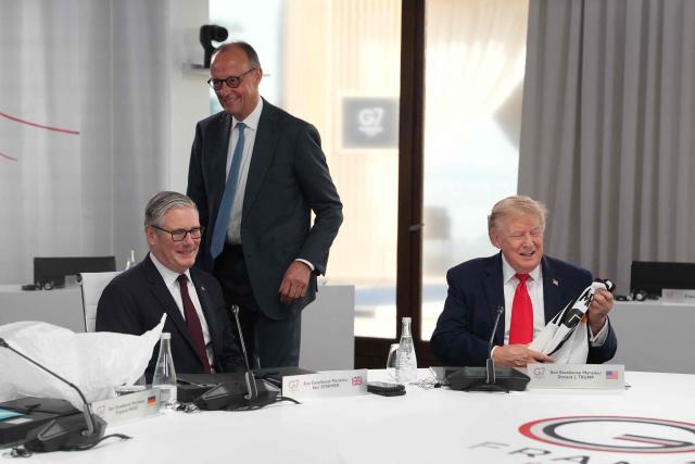 Germany's Chancellor Friedrich Merz (C) presents US President Donald Trump (R) with a German national football team jersey with the number 47 on it as British Prime Minister Keir Starmer (L) looks on during a working session at the G7 summit in Evian-les-Bains, central-eastern France on June 16, 2026. (Photo by Thibault Camus / POOL / AFP)