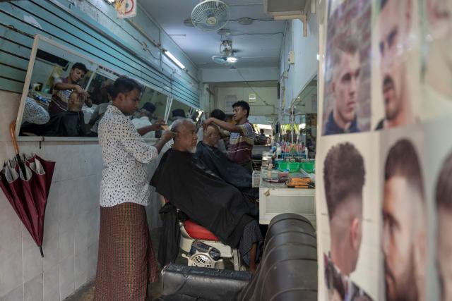People have their hair cut at a barber shop in Yongon on June 16, 2026. (Photo by Sai Aung MAIN / AFP)