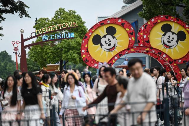 People walk past a Mickey Mouse sign as they enter Shanghai Disney Resort in Shanghai on June 16,  2026. (Photo by Jade Gao / AFP)
