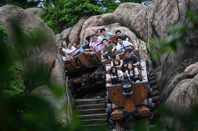Visitors ride the 'Seven Dwarfs Mine Train' at Shanghai Disney Resort in Shanghai on June 16, 2026. (Photo by Jade Gao / AFP)