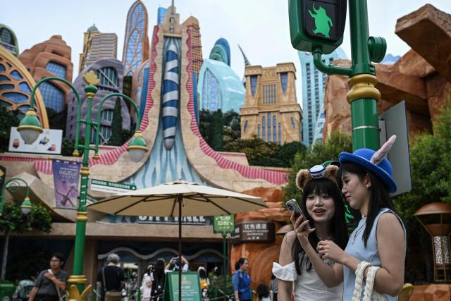 Visitors look at a phone in the Zootopia land of Shanghai Disney Resort in Shanghai on June 16, 2026. (Photo by Jade Gao / AFP)