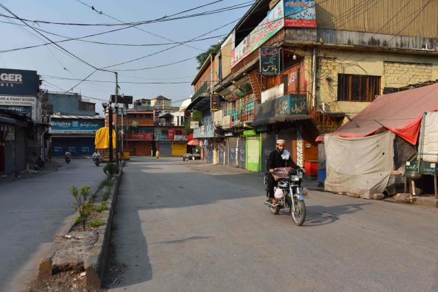 A commuter rides past closed shops at a deserted marketplace in Muzaffarabad, the capital of Pakistan-administered Kashmir on June 16, 2026 amid protests called by the Joint Awami Action Committee (JAAC) following the group’s ban under anti-terrorism laws by local authorities. The death toll from clashes between police and members of a banned protest movement in Pakistan-administered Kashmir has risen to 20, according to an AFP tally on June 12 based on official figures. (Photo by AFP)