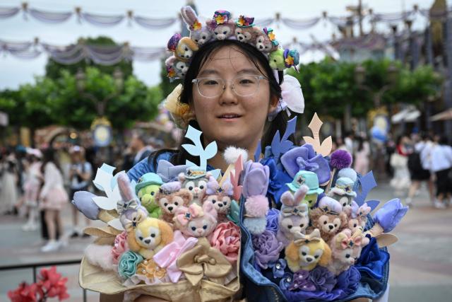 A visitor wearing a Duffy and Friends headband holds two matching plush bouquets at Shanghai Disney Resort in Shanghai on June 16, 2026. (Photo by Jade Gao / AFP)
