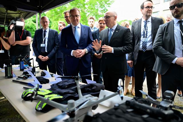 German Interior Minister Alexander Dobrindt (C-L) and Sinan Selen (C-R), President of the Federal Office for the Protection of the Constitution (Bundesamt für Verfassungsschutz),  look at an exhibit of various defensive weapons including a drone (front C) on display during the inauguration of a Joint Center for Countering Hybrid Threats (GAZ Hybrid) in Berlin on June 16, 2026. The core mission of GAZ Hybrid is, according to the Interior Ministry, to identify and combat espionage, sabotage, disinformation, proliferation, transnational repression, state terrorism, and other forms of hybrid threats. (Photo by John MACDOUGALL / AFP)