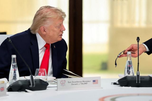US President Donald Trump looks at a watch during a work lunch as part of the G7 summit, in Evian, eastern France, on June 16, 2026. A G7 summit is set to take place June 15 to 17 in the French town of Evian-les-Bains near Switzerland and it will be attended by country leaders as well as the EU's foreign policy chief and ministers from Brazil, Canada, the United Arab Emirates and Turkey. (Photo by Christian Hartmann / POOL / AFP)