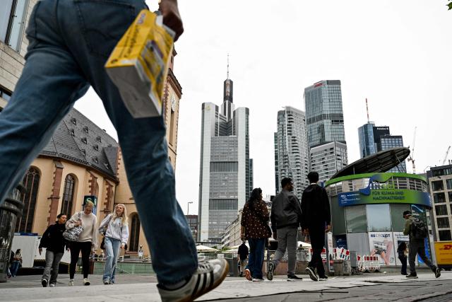 A pedestrian walks near the Commerzbank building (C) in the banking district in Frankfurt am Main, western Germany, on June 16, 2026. Tuesday, June 16, marks the final day for UniCredit's hostile and highly political takeover offer for Commerzbank, as Italy's second-largest bank has its sights on an ambitious pan-European banking merger. (Photo by Kirill KUDRYAVTSEV / AFP)