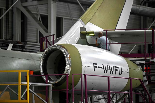 A technician inspects the tail of a Falcon 6X business aircraft with a torch on an assembly line at the Dassault Aviation plant in Merignac, southwestern France on June 16, 2026. (Photo by Christophe ARCHAMBAULT / AFP)