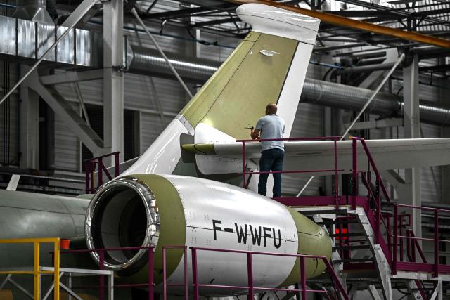 A technician inspects the tail of a Falcon 6X business aircraft with a torch on an assembly line at the Dassault Aviation plant in Merignac, southwestern France on June 16, 2026. (Photo by Christophe ARCHAMBAULT / AFP)