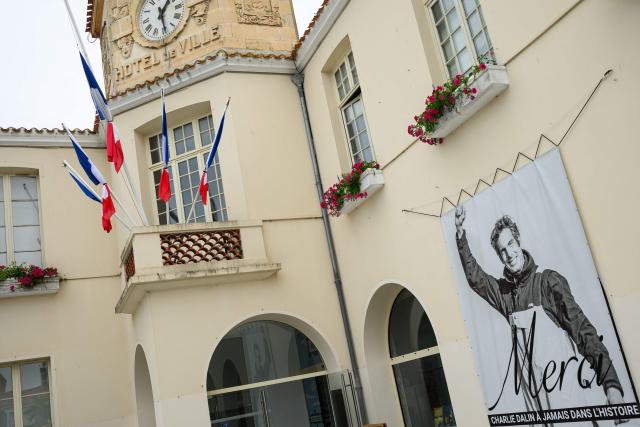 This photograph shows flags at half-staff and a poster in memory of late French skipper Charlie Dalin displayed in front of the city hall in Les Sables-d'Olonne, western France on June 16, 2026. French offshore sailor and Vendee Globe 2024/2025 winner Charlie Dalin has died in Quimper, western France, aged 42, from cancer, his family announced on June 11, 2026. (Photo by Loic VENANCE / AFP)