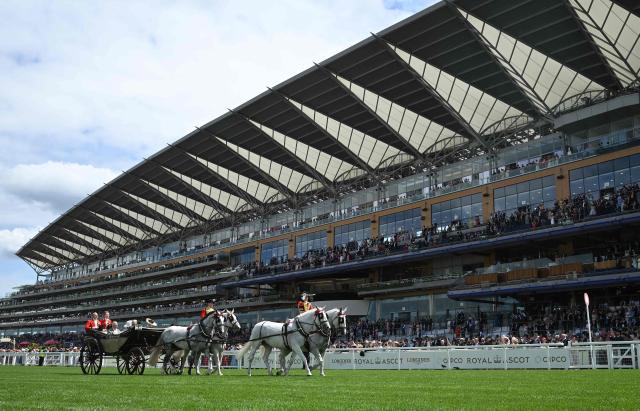 Britain's King Charles III and Britain's Queen Camilla travel in a horse-drawn carriage across the finish line, ahead of racing, on the first day of the Royal Ascot horse racing meeting in Ascot, west of London, on June 16, 2026. (Photo by JUSTIN TALLIS / AFP)