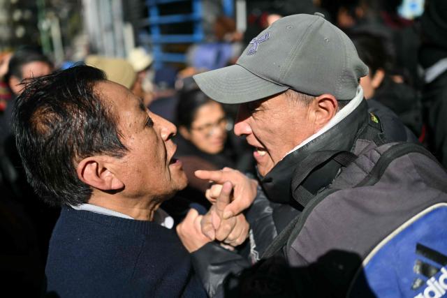 Two men argue while queueing outside a state-owned supermarket following a government announcement that chicken would be sold there, in La Paz on June 16, 2026. For weeks, protesters demanding that US-backed conservative President Rodrigo Paz's fledgling government address a deep economic crisis, while others called for his resignation, have marched and set up roadblocks, bringing Bolivia to a near standstill, driving up food and fuel prices and causing shortages of basic goods. (Photo by Marvin RECINOS / AFP)