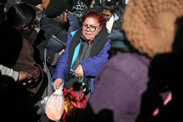 A woman struggles to leave through the crowd after buying a chicken at a state-owned supermarket, in La Paz on June 16, 2026. For weeks, protesters demanding that US-backed conservative President Rodrigo Paz's fledgling government address a deep economic crisis, while others called for his resignation, have marched and set up roadblocks, bringing Bolivia to a near standstill, driving up food and fuel prices and causing shortages of basic goods. (Photo by Marvin RECINOS / AFP)