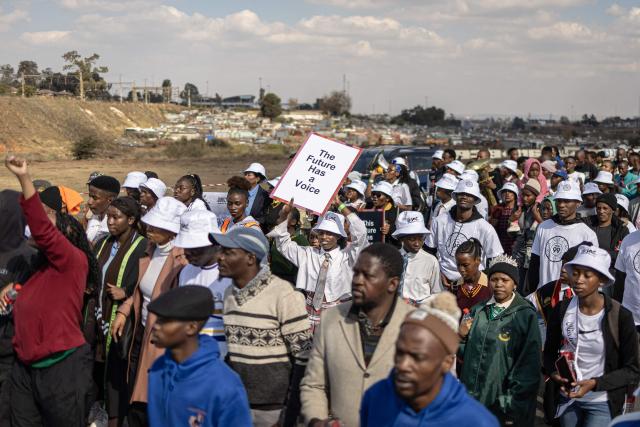 Attendees walk with placards during a march marking the 50th anniversary of the June 16, 1976 Soweto Uprising, organised by 1976 @ Fifty, in Soweto near Johannesburg, on June 16, 2026. June 16 is commemorated as Youth Day in South Africa, honouring the thousands of Black school students who took to the streets in 1976 to protest against the apartheid government’s imposition of Afrikaans as a language of instruction, and the students who were killed and injured when police opened fire on the demonstration. (Photo by EMMANUEL CROSET / AFP)