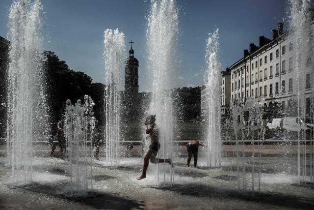 (FILES) Children play as they cool off in a fountain in Lyon on May 27, 2026 as a heatwave hits France. The heatwave that is expected to hit France from June 17, 2026 could send temperatures soaring to "peaks of 40°C" on June 21, 2026, coinciding with the summer solstice, Météo-France has warned. (Photo by Jeff PACHOUD / AFP)
