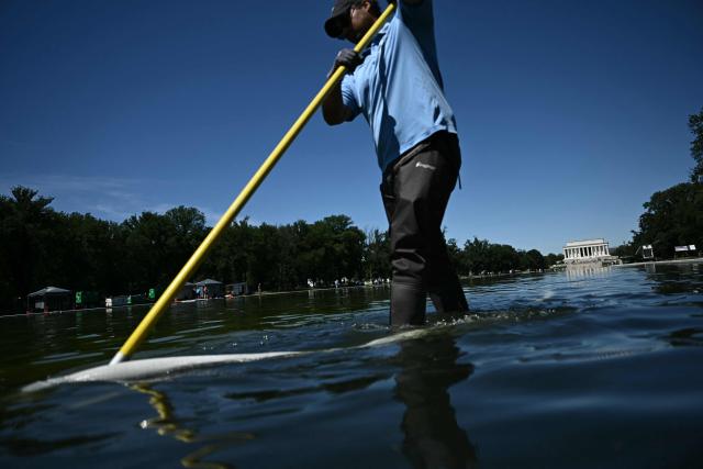 National Park Service workers push algae towards an aeration area in the center of the Lincoln Memorial Reflecting Pool following the completion of recent renovations in Washington, DC, on June 16, 2026. The reflecting pool project, undertaken as part of President Donald Trump’s preparations for the nation’s 250th anniversary, began in April and was completed last week. (Photo by Brendan SMIALOWSKI / AFP)