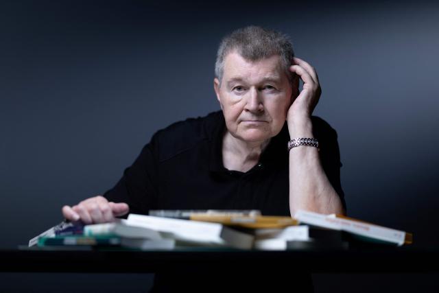 French writer Antoine Volodine poses for pictures with 11 books that will be simultaneously released in the fall of 2026, each manuscript will be published by a different publisher under the collective byline Infernus Iohannes, in Paris on June 16, 2026. (Photo by Joel Saget / AFP)