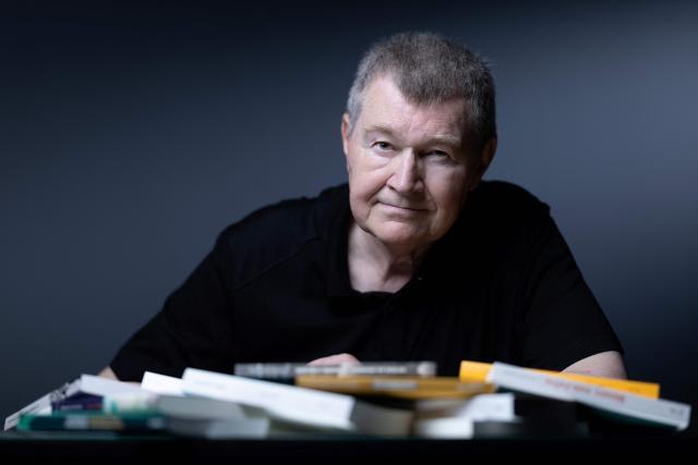 French writer Antoine Volodine poses for pictures with 11 books that will be simultaneously released in the fall of 2026, each manuscript will be published by a different publisher under the collective byline Infernus Iohannes, in Paris on June 16, 2026. (Photo by Joel Saget / AFP)