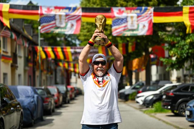 German football fan Achim Klimmeck shows a replica World Cup trophy in the Rullichstrasse where he hung up flags of Germany and other european countries in Essen on June 16, 2026. Over 500 flags can be seen in the residential street during the during the FIFA World Cup 2026 football championship. (Photo by Ina FASSBENDER / AFP)