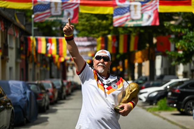 German football fan Achim Klimmeck shows a replica World Cup trophy in the Rullichstrasse where he hung up flags of Germany and other european countries in Essen on June 16, 2026. Over 500 flags can be seen in the residential street during the during the FIFA World Cup 2026 football championship. (Photo by Ina FASSBENDER / AFP)