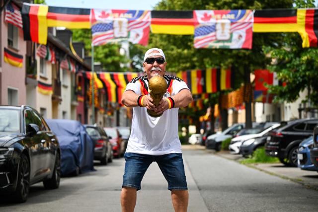 German football fan Achim Klimmeck shows a replica World Cup trophy in the Rullichstrasse where he hung up flags of Germany and other european countries in Essen on June 16, 2026. Over 500 flags can be seen in the residential street during the during the FIFA World Cup 2026 football championship. (Photo by Ina FASSBENDER / AFP)