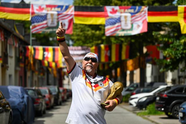 German football fan Achim Klimmeck shows a replica World Cup trophy in the Rullichstrasse where he hung up flags of Germany and other european countries in Essen on June 16, 2026. Over 500 flags can be seen in the residential street during the during the FIFA World Cup 2026 football championship. (Photo by Ina FASSBENDER / AFP)