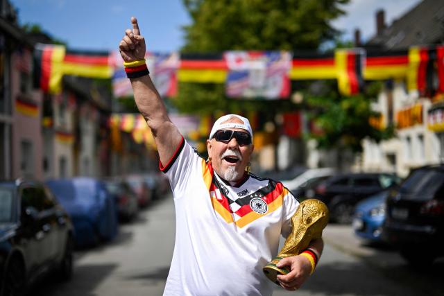 German football fan Achim Klimmeck shows a replica World Cup trophy in the Rullichstrasse where he hung up flags of Germany and other european countries in Essen on June 16, 2026. Over 500 flags can be seen in the residential street during the during the FIFA World Cup 2026 football championship. (Photo by Ina FASSBENDER / AFP)