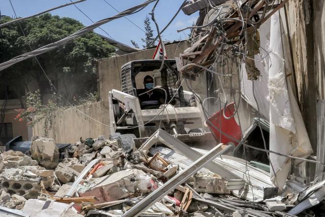 A worker pilots a small excavator to remove the rubble of a destroyed building in the village of Deir Qanoun al-Nahr in southern Lebanon on June 16, 2026. Lebanese state media said that Israeli strikes killed at least four people in the Nabatieh area of the country's south on June 16, despite an announcement that a US-Iran deal included the Israel-Hezbollah war. While violence has declined in Lebanon since the agreement between the US and Iran was announced, Israeli strikes on the south have now killed at least five people since June 15. (Photo by MAHMOUD ZAYYAT / AFP) / 
