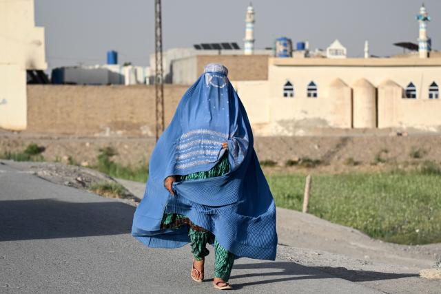 An Afghan burqa-clad woman walks along a road at Kolcha Abad village in the Dand district of Kandahar on June 16, 2026. (Photo by Sanaullah SEIAM / AFP)
