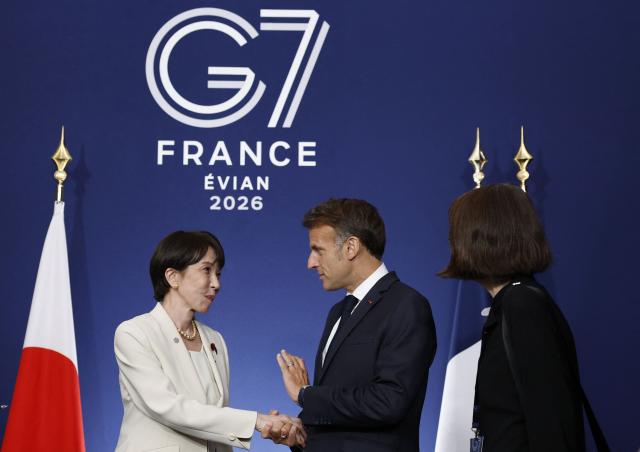 France's President Emmanuel Macron (C) shakes hands with Japan's Prime Minister Sanae Takaichi (L) during a bilateral meeting on the sideline of the G7 summit, in Evian, eastern France, on June 16, 2026. A G7 summit is set to take place June 15 to 17 in the French town of Evian-les-Bains near Switzerland and it will be attended by country leaders as well as the EU's foreign policy chief and ministers from Brazil, Canada, the United Arab Emirates and Turkey. (Photo by Yoan VALAT / POOL / AFP)