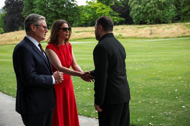 British Prime Minister's wife Victoria Starmer (C) shakes hands with Ukraine's President Volodymyr Zelensky (R) as Britain's Prime Minister Keir Starmer (L) looks on during a meeting on the sideline of the G7 summit, in Evian, eastern France, on June 16, 2026. A G7 summit is set to take place June 15 to 17 in the French town of Evian-les-Bains near Switzerland and it will be attended by country leaders as well as the EU's foreign policy chief and ministers from Brazil, Canada, the United Arab Emirates and Turkey. (Photo by Isabel Infantes / POOL / AFP)