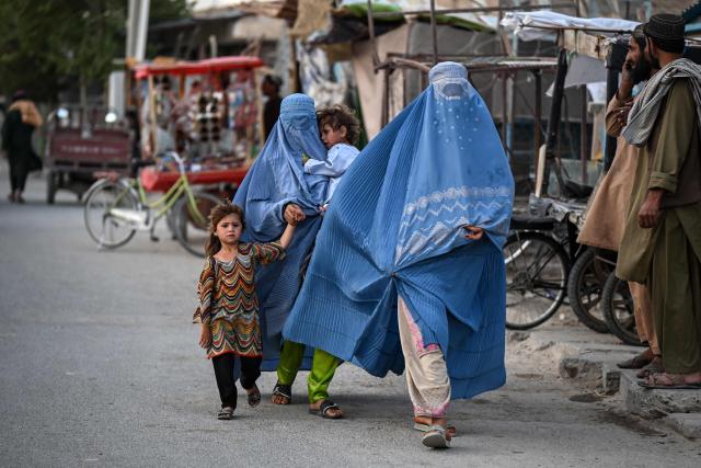 Afghan women clad in burqas, along with their children, walk along a road in Spin Ziyarat village in the Dand district of Kandahar on June 16, 2026. (Photo by Sanaullah SEIAM / AFP)