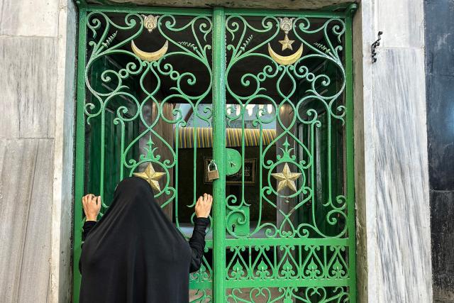 A woman looks through an iron gate during celebrations of the Islamic Hijri New Year at the Ibrahimi Mosque, known to Jews as the Cave of the Patriarchs, located inside the Israeli-controlled H2 sector of the occupied West Bank city of Hebron, on June 16, 2026. Israel's finance minister said on June 16, he had stripped Palestinians of authority over the site of the Cave of Patriarchs, known to Muslims as the Ibrahimi Mosque, in the occupied West Bank. The move to transfer management of the site to an Israeli committee controlled by the far-right minister, drew swift condemnation from the Palestinian Authority. (Photo by Hazem BADER / AFP)