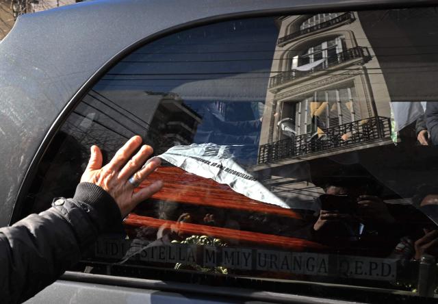 A woman touches the hearse carrying the coffin of Taty Almeida, the late president of the Madres de Plaza de Mayo human rights association, as the cortege drives past the home of former Argentine President Cristina Fernandez de Kirchner on its way to the burial in Buenos Aires, on June 16, 2026. Almeida died on June 14, 2026 at the age of 95, after more than four decades as one of the most prominent voices against the crimes of Argentina's last dictatorship since she lost in 1975 her son Alejandro, a member of the guerrilla group Revolutionary People's Army (ERP), kidnapped by the right-wing paramilitary organization Triple A. (Photo by Luis ROBAYO / AFP)